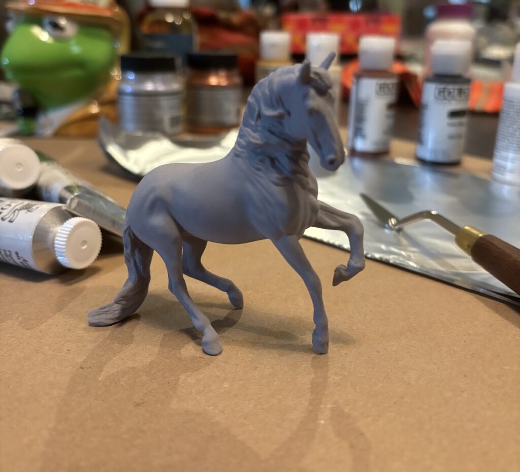 A photo of the primered horse sitting on the kitchen table with all of the paint supplies in the background.