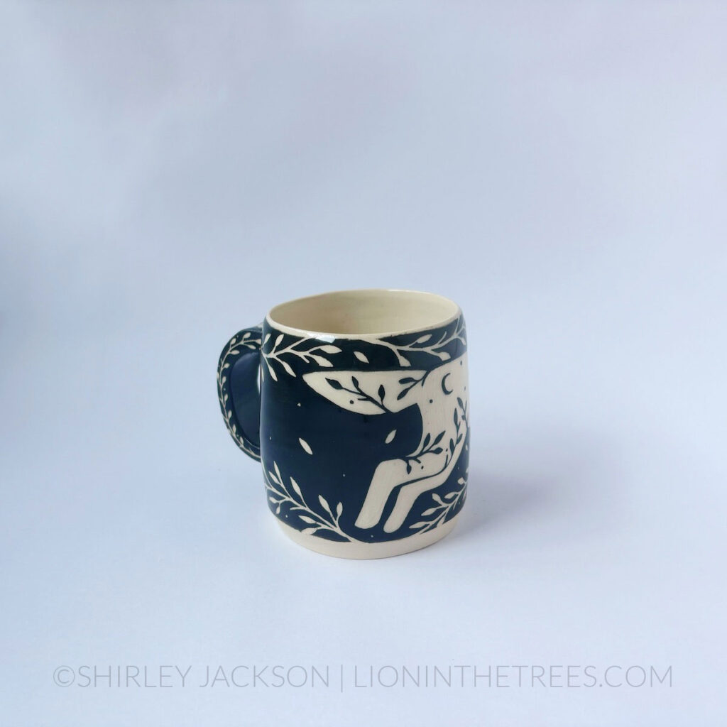 Black and cream sgraffito mug featuring my Running Wolf motif and floral elements