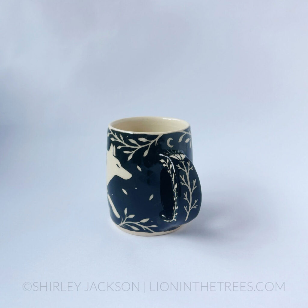 Black and cream sgraffito mug featuring my Running Wolf motif and floral elements