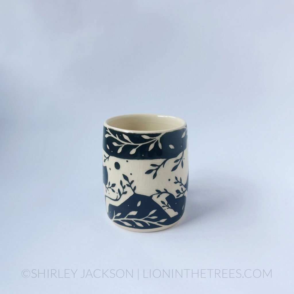 Black and cream sgraffito mug featuring my Running Wolf motif and floral elements