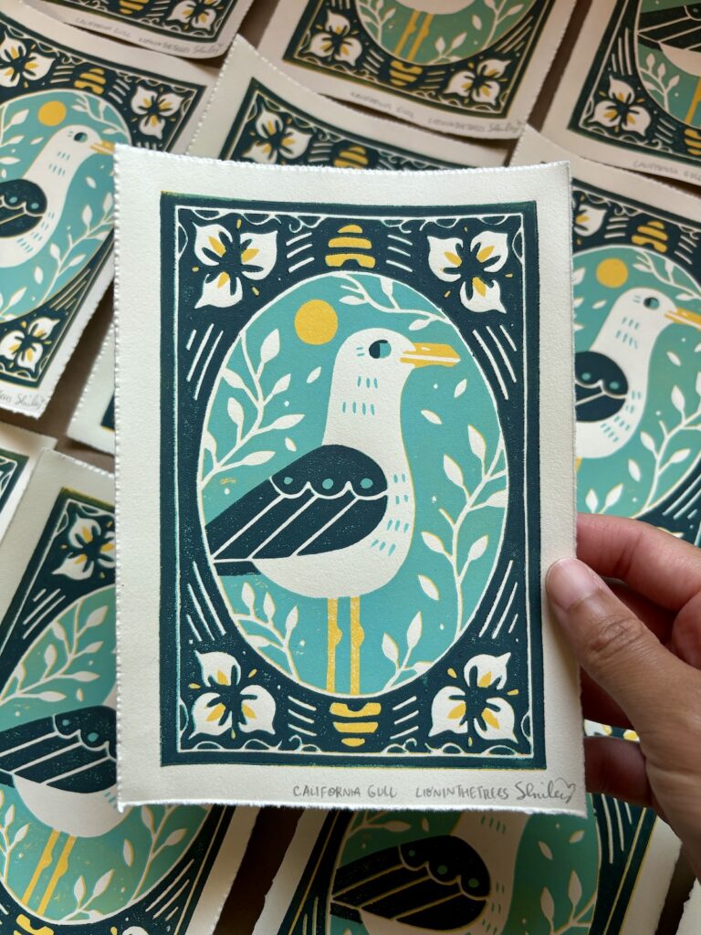 Linoblock relief print of a California Gull done with a turquoise, yellow, and dark blue-green