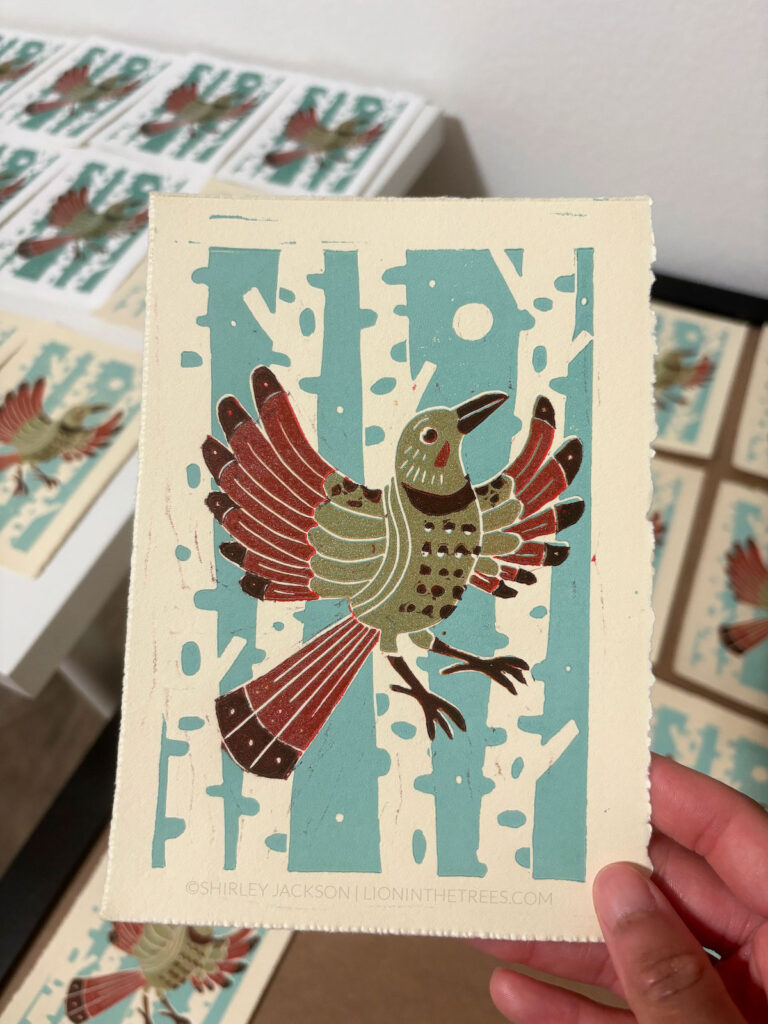 Lino-block relief print of a Red Shafted Northern Flicker done with light blue, a coppery light brown, red, and a dark-red maroon.