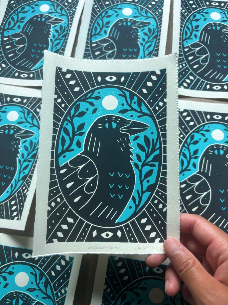 Linoblock relief print of an American Crow done with a blue and black ink.