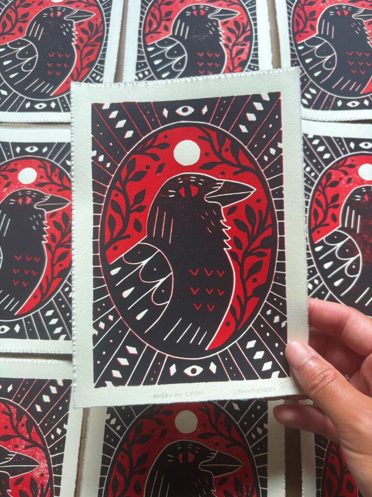 Linoblock relief print of an American Crow done with a golden red and black.
