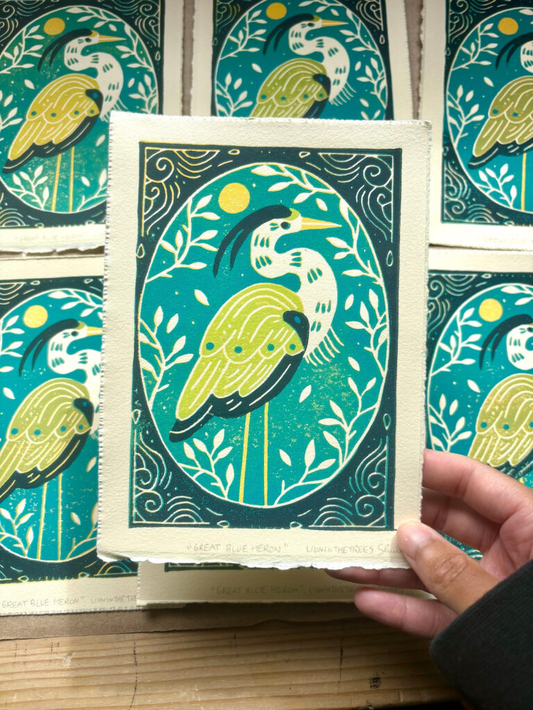 Linoblock relief print of a Great Blue Heron done with a yellow, light green, turquoise, and dark blue-green ink.