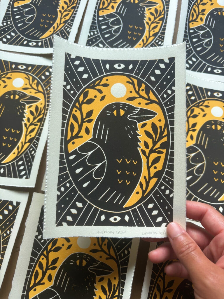 Linoblock relief print of an American Crow done with a golden yellow and black.