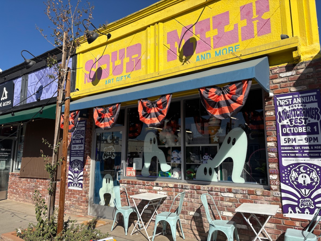 The front of Sour Milk shop which shows a variety of giant Fresno Nightcrawler window clings, as well as the festival banner on either side of the building.