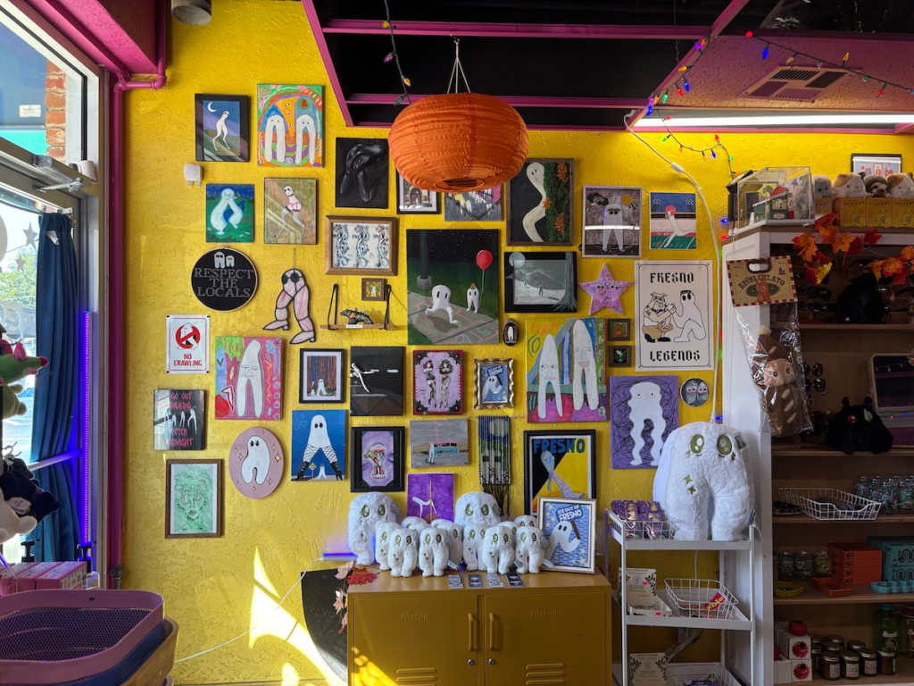 A yellow wall with a gallery style layout featuring a wide variety of traditional artwork of the Fresno Nightcrawler.