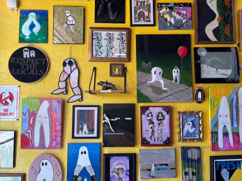 A close up of some of the art pieces. There are embroideries, a ceramic sculpture, and a plethora of paintings.