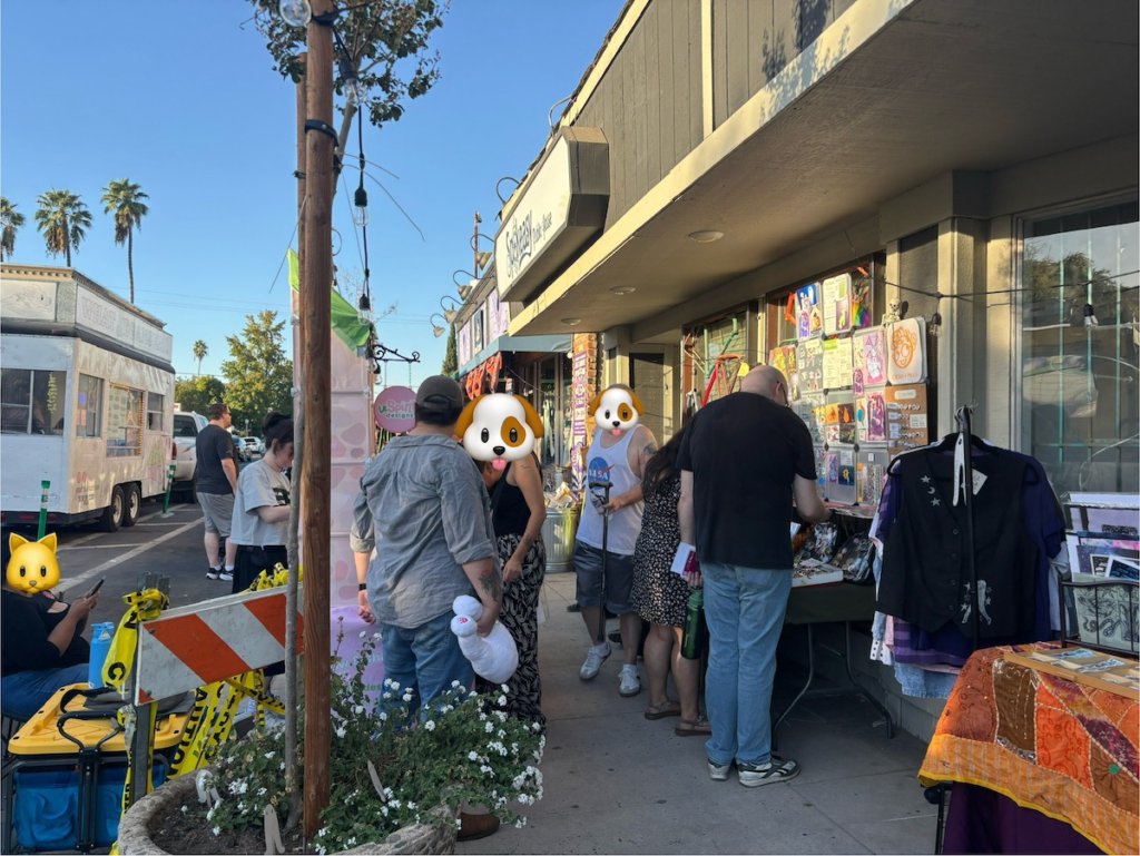 Another shot of folks further down the sidewalk gathered around more vendors and perusing their wares.