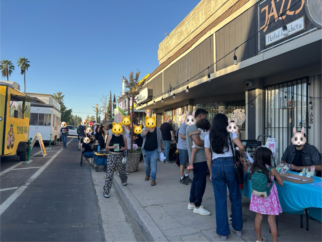 Another shot that's further away showing more people as well as two food trucks parked on the side of the street.